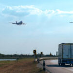 Flying passenger jet plane on the sky over the container truck running on the road, transport and logistic concept.